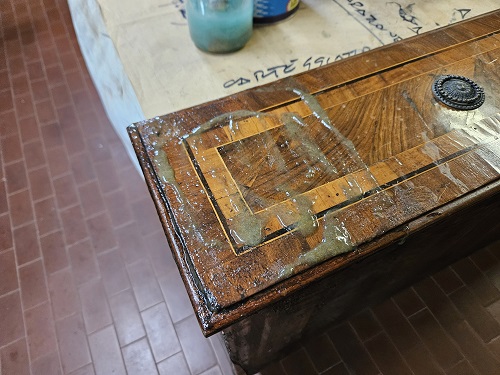 La sverniciatura di un cassetto neoclassico lastronato.